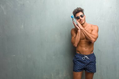 Bir grunge duvara yorgun ve çok uykulu bir mayo giyen genç atletik erkek jest uyumak rahat ve huzurlu, seyir