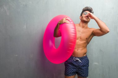 Rahat ve neşeli, gülen ve having fun, grunge duvara bir mayo giyen genç atletik adam kendinden emin ve başarılı hissediyor