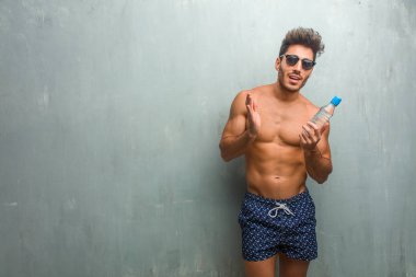 Bir grunge duvara bir mayo giyen genç atletik adam şaşırttı ve şok, kazanmak kavramı geniş gözlü, heyecanlı bir teklif veya yeni bir iş arıyorum