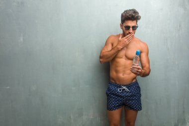 Bir grunge duvara bir mayo giyen genç atletik adam şaşırttı ve şok, kazanmak kavramı geniş gözlü, heyecanlı bir teklif veya yeni bir iş arıyorum