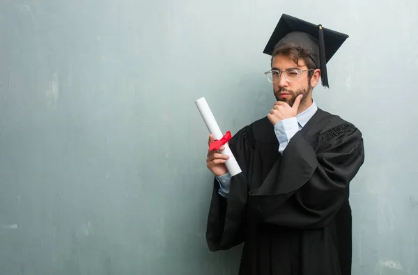 Young Graduated Man Grunge Wall Copy Space Thinking Looking Confused — Stock Photo, Image