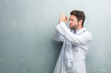 Gizleme ve gözlerini kısarak samimi bir doktor adam bir boşluk seyir bir kopya alanı ile bir grunge duvara