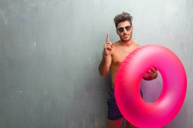 Gösterilen bir numaralı simgesi sayma, kavramı matematik, kendinden emin ve neşeli bir grunge duvara bir mayo giyen genç atletik adam