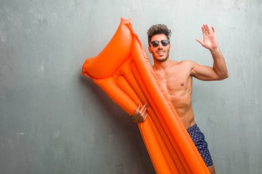 Ağzı açık, atlama ve gururlu bir mayo mutlu, sürpriz bir teklif ya da bir promosyon tarafından bir grunge duvar çığlık karşı giyen genç atletik adam