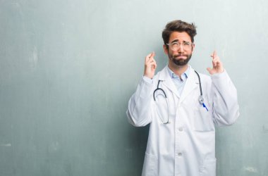 Genç dostu Doktor adam onun parmak kapısı bir kopya alanı ile bir grunge duvara dilek gelecekteki projelerde, gözleri kapanış endişeli, gergin ifade heyecanlı şanslı olmak