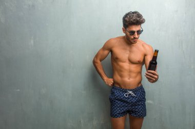 Öfkeli, negatif ve çılgın çığlık bir grunge duvara çok kızgın ve üzgün, çok gergin bir mayo giyen genç atletik adam