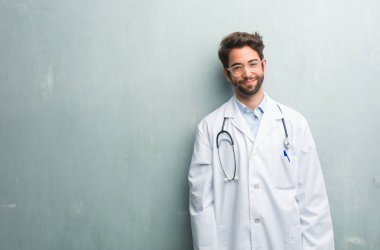 Bir grunge duvara neşeli bir kopya alanı ile ve büyük bir gülümsemeyle, kendine güvenen, samimi ve içten, samimi bir doktor adam pozitifliği ve başarı ifade