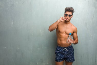 Bir sırrı saklamak veya soran sessizlik, ciddi bir yüz, itaat kavram için bir grunge duvara bir mayo giyen genç atletik adam