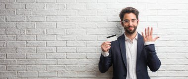 Sayma, kavramı matematik, kendinden emin ve neşeli bir beyaz tuğla duvar gösteren sayı beş, sembol karşı bir takım elbise giymiş genç iş adamı
