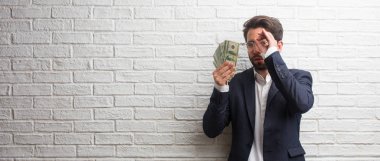 Gizleme ve şaşı bir boşluk seyir bir beyaz tuğla duvara bir takım elbise giymiş genç iş adamı