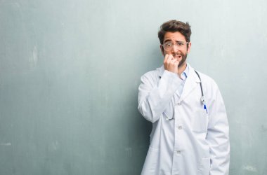 Panik ve stres genç dostu Doktor adam çivi, gergin ve çok endişeli ve gelecek için korkmuş ısırma bir kopya alanı ile bir grunge duvara hisseder