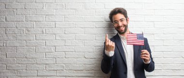 Pozitif ve güler yüzlü bir beyaz tuğla duvar davet gel, kendinden emin ve gülümseyen bir hareketi el ile yapmak için karşı bir takım elbise giymiş genç iş adamı