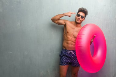 Duygu üzgün ve korkmuş bir silah parmak ile şekillendirme bir intihar jest yapma bir grunge duvara bir mayo giyen genç atletik adam