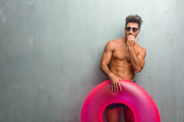 Panik ve stres bir grunge duvara çivi, gergin ve çok endişeli ve gelecek için korkmuş ısırma bir mayo giyen genç atletik adam geliyor