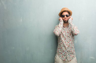 Eller, kızgın ve bazı ses işitme yorgun kulaklarıyla kapsayan bir renkli gömlek giymiş genç seyahat adam