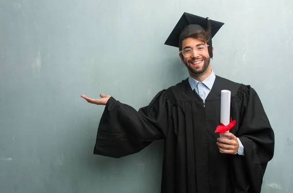 Young Graduated Man Grunge Wall Copy Space Holding Something Hands — Stock Photo, Image