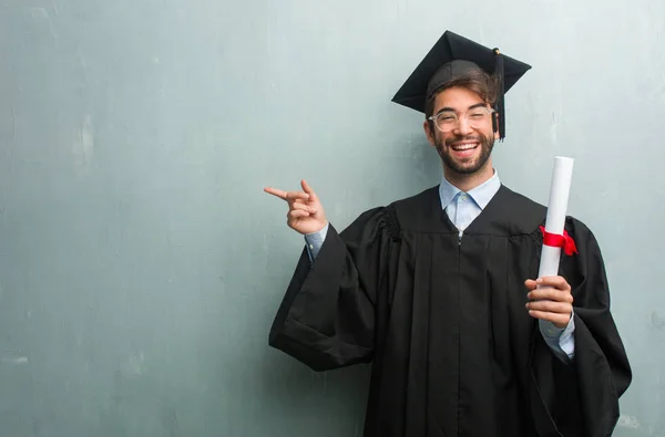 Młodzi Ukończył Człowiek Ścianę Grunge Miejsca Kopiowania Wskazując Bok Uśmiechając — Zdjęcie stockowe