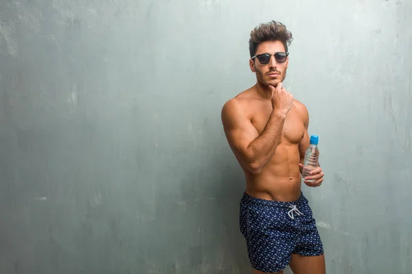 Young Athletic Man Wearing Swimsuit Grunge Wall Thinking Looking Confused — Stock Photo, Image