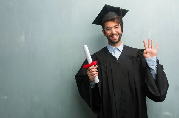 Young graduated man against a grunge wall with a copy space showing the number four, symbol of counting, concept of mathematics, confident and cheerful