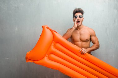 Ağzı açık, atlama ve gururlu bir mayo mutlu, sürpriz bir teklif ya da bir promosyon tarafından bir grunge duvar çığlık karşı giyen genç atletik adam