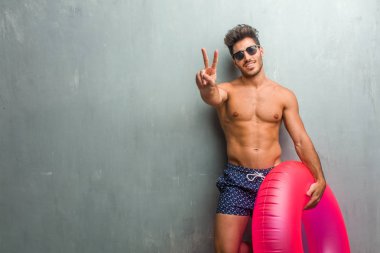 Sayma, kavramı matematik, kendinden emin ve neşeli bir grunge duvar gösteren sayı iki, sembol karşı bir mayo giyen genç atletik adam