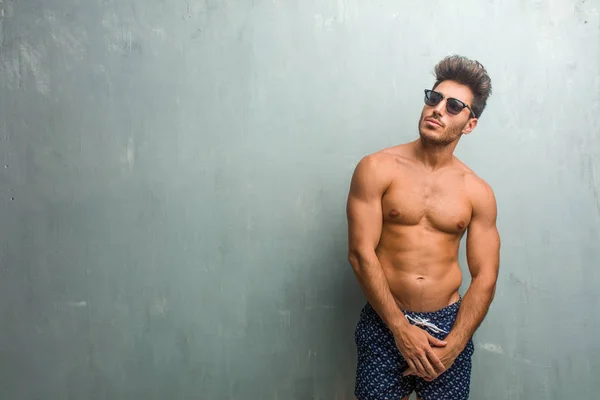 Young Athletic Man Wearing Swimsuit Grunge Wall Doubting Confused Thinking — Stock Photo, Image