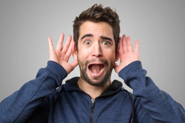 Genç adam gri arka plan üzerinde dinleme