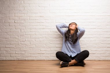 Bir tuğla duvara sinirli ve umutsuz, kızgın ve üzgün elle başındaki Genç Hintli kadın sit