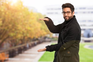 Genç adam bir şey tutuyor.