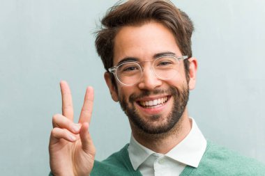 Genç yakışıklı girişimci adam yüz eğlence ve mutlu, pozitif ve doğal, zafer, barış kavramı bir jesti yapıyor