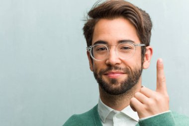 Genç yakışıklı girişimci adam yüz gösterilen bir numaralı simgesi sayma, kavramı matematik, kendinden emin ve neşeli portre