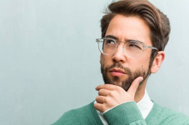 Genç yakışıklı girişimci adam closeup şüphe yüz ve kafası karışık, bir fikir düşünce ya da bir şey hakkında endişeli