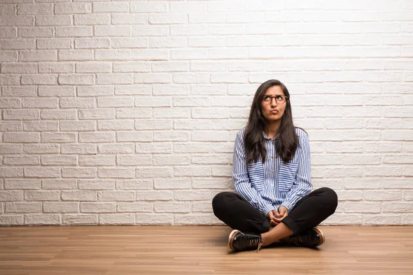 Jonge Indiase Vrouw Zitten Tegen Een Bakstenen Muur Twijfelen Verward — Stockfoto