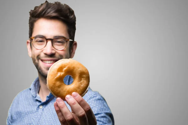 Jonge Man Het Aanbieden Van Een Donut Grijze Achtergrond — Stockfoto