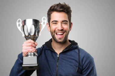 mutlu genç adam bir kupa gri arka plan üzerinde tutan