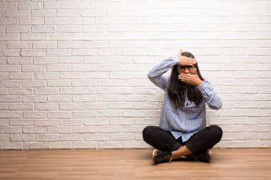 Genç Hintli kadın oturup bir boşluk seyir bir tuğla duvara gizleme ve şaşı