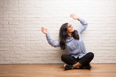 Genç Hintli kadın oturup karşı bir tuğla duvar dinleme müzik, dans ve having fun, taşıma, bağırarak ve mutluluk, Özgürlük kavramı ifade