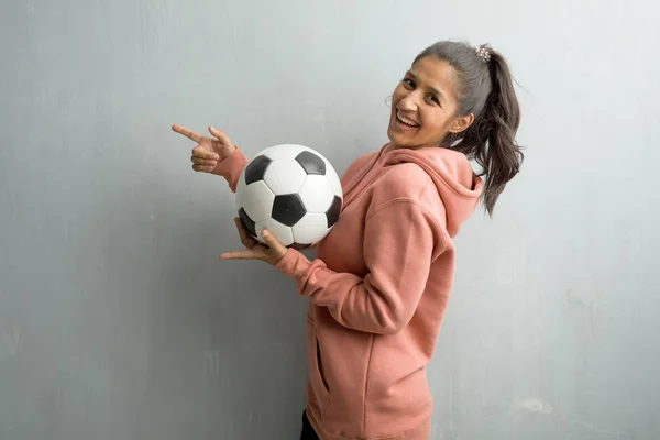 Młoda Kobieta Sportowy Indyjski Pod Ścianą Wskazując Bok Uśmiechający Się — Zdjęcie stockowe