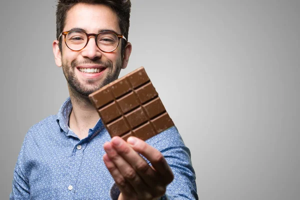 Joven Sosteniendo Una Barra Chocolate Sobre Fondo Gris — Foto de Stock