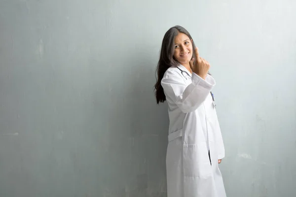 Young indian doctor woman against a wall inviting to come, confident and smiling making a gesture with hand, being positive and friendly