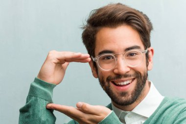 Elleriyle bir şey tutan, bir ürün, gülümseyen ve neşeli gösterilen, hayali bir nesne sunan genç yakışıklı girişimci adam yüz portre