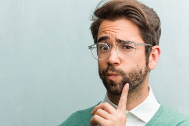 Genç yakışıklı girişimci adam closeup şüphe yüz ve kafası karışık, bir fikir düşünce ya da bir şey hakkında endişeli