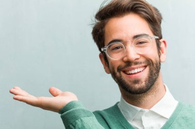 Elleriyle bir şey tutan, bir ürün, gülümseyen ve neşeli gösterilen, hayali bir nesne sunan genç yakışıklı girişimci adam yüz portre