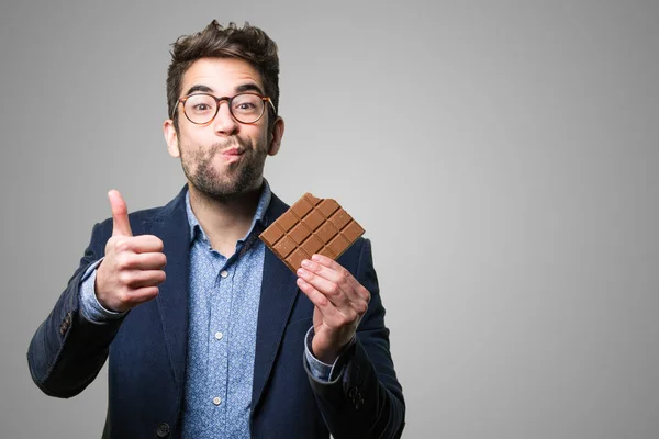 Jovem Comendo Uma Barra Chocolate Fundo Cinza — Fotografia de Stock