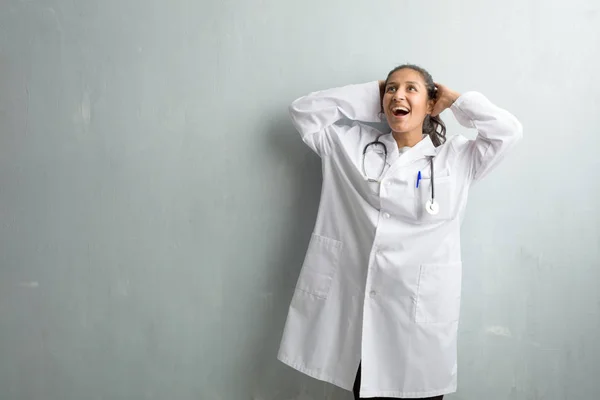 Young indian doctor woman against a wall surprised and shocked, looking with wide eyes, excited by an offer or by a new job, win concept