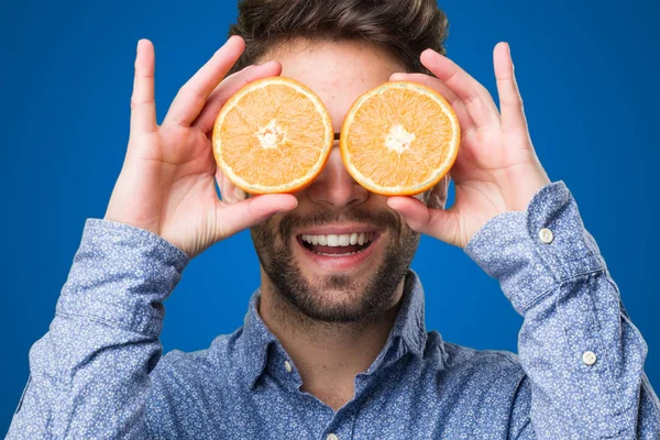 Joven Cubriendo Sus Ojos Con Naranjas Sobre Fondo Azul — Foto de Stock