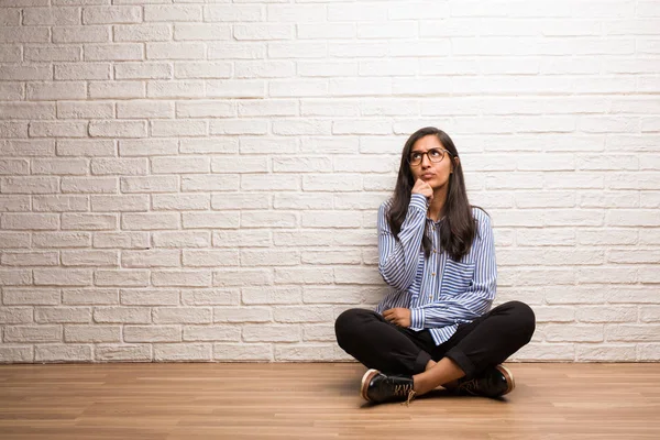 Jonge Indiase Vrouw Zitten Tegen Een Bakstenen Muur Twijfelen Verward — Stockfoto