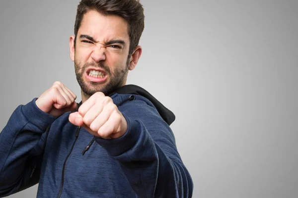 Joven Golpeando Sobre Fondo Gris —  Fotos de Stock