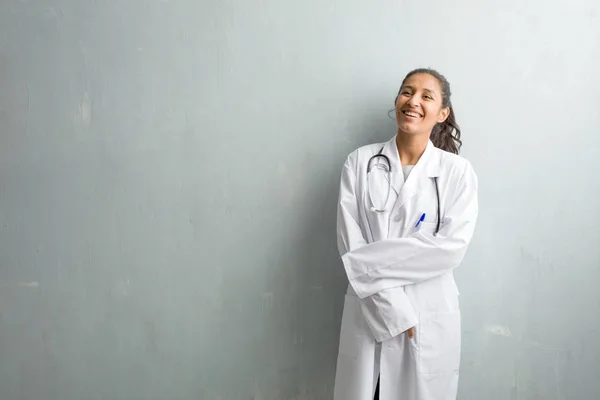 Young indian doctor woman against a wall cheerful and with a big smile, confident, friendly and sincere, expressing positivity and success