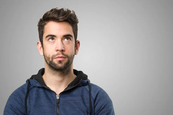 young man thinking on grey background